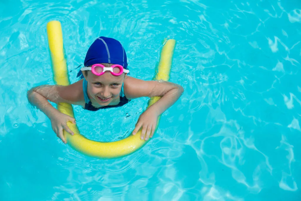 une enfant apprend à nager avec une frite pour piscine